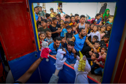 Un groupe d'enfants et d'adultes assiste avec émerveillement à un spectacle de marionnettes, illustrant le pouvoir rassembleur de l'art et de la culture